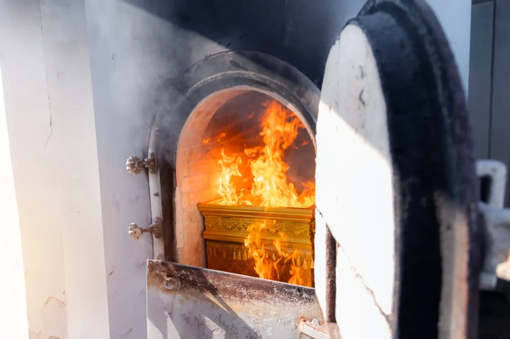 An open cremation oven with a casket burning inside